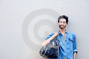 Young man standing with travel bag over shoulder