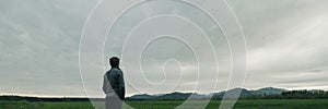 Young man standing under grey cloudy sky