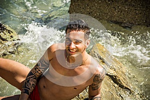 Young man standing in water by sea or ocean shore,