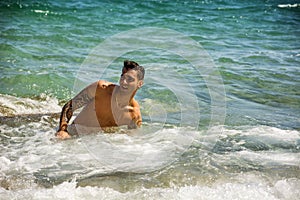 Young man standing in water by sea or ocean shore,