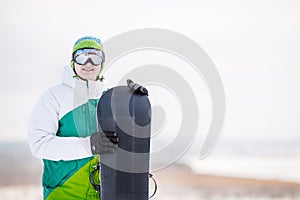 Young man standng on the snow with snowboard