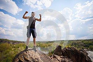 Young man stands on the top of the rock