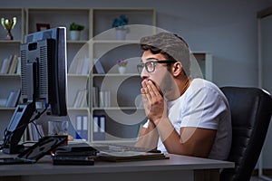 The young man staying late in office to do overtime work