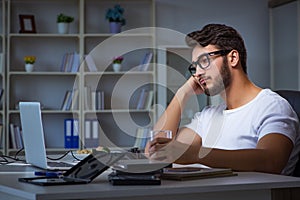 The young man staying late in office to do overtime work