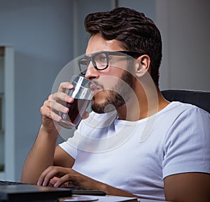 Young man staying late in office to do overtime work