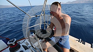 Young man steers a sailing yacht boat in the open sea. Sport.