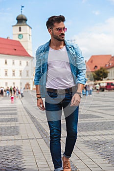 Young man stepping forward on street looks down to side