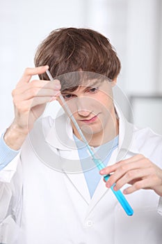 Young man stirring blue liquid