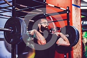 Young man straining to lift heavy weights during a workout session in a gym