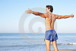 Young man stretching on beach