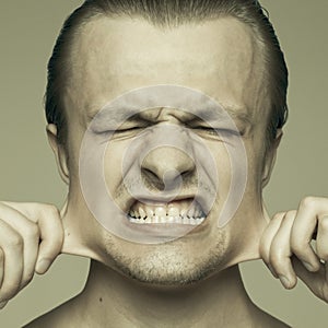 Young man stretching out his cheeks