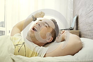 Young man stretching while waking up in the morning. Man yawning while waking up. Lazy young man in sleep. man yawns and