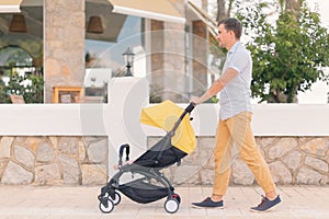 Young man strolling pushchair with sleeping baby