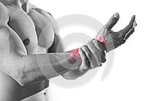 Young man with strong muscle body holding damaged wrist suffering pain in sport injury