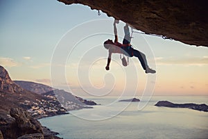 Young man struggling to climb challenging route on cliff