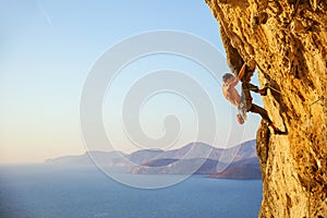 Young man struggling to climb challenging route on cliff