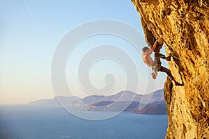 Young man struggling to climb challenging route on cliff photo