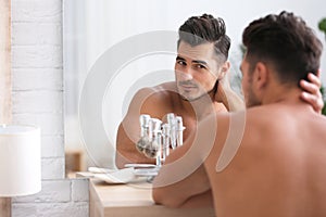 Young man with stubble ready for shaving near mirror