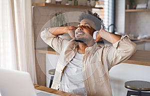 Young man student with laptop and headphones indoors at home, reating after studying.