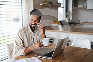 Young man student with laptop and smartphone working indoors at home, home office concept.