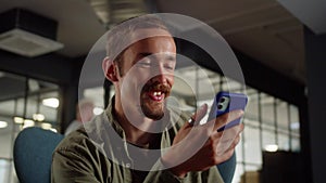 A young man-student sits on the chair and talking to his friends on the video call, close up