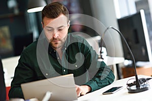 Young man studying with laptop computer on white desk.