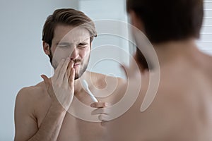 Young man suffer from gums inflammation brushing teeth photo