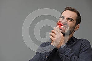 Young man suffering from acute toothache on grey background, space for text