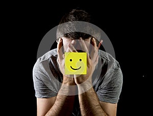 Young man suffering depression and stress alone with smiley face post it note