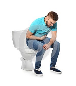 Young man suffering from digestive disorder on toilet bowl