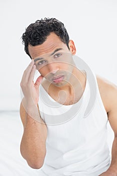 Young man suffering from headache in bed