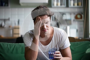 Young man suffering from headache, migraine or hangover at home