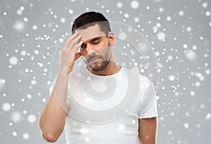 Young man suffering from headache over snow