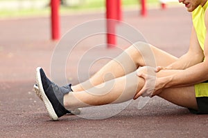 Young man suffering from knee pain on sports ground