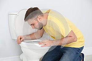 Young man suffering from nausea over toilet bowl