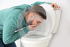 Young man suffering from nausea over toilet bowl