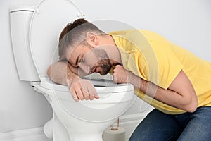 Young man suffering from nausea over toilet bowl