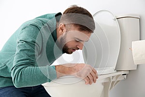 Young man suffering from nausea over toilet bowl