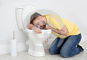 Young man suffering from nausea over toilet bowl