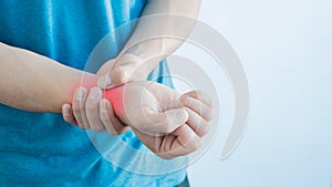 A young man suffering from pain, the man`s wrist was in excruciating pain, and held his hand on a white background.