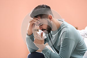 Young man suffering from runny nose indoors