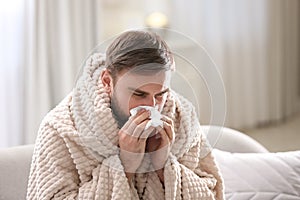 Young man suffering from runny nose in living room