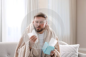 Young man suffering from runny nose in room