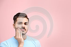 Young man suffering from strong tooth pain on color background