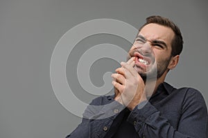 Young man suffering from strong tooth pain on grey background