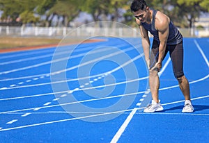 young man suffering from sudden knee and leg pain during the workout at the stadium