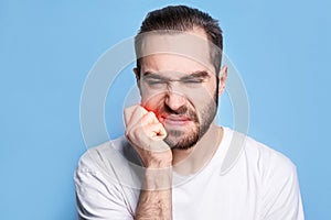 Young man suffering from toothache on blue background