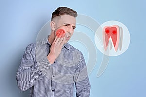 Young man suffering from toothache on light blue background
