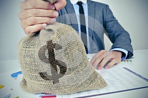 Young man in suit with a burlap money bag with the US dollar sig