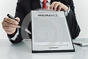 Young man in suit in his office showing an insurance policy and